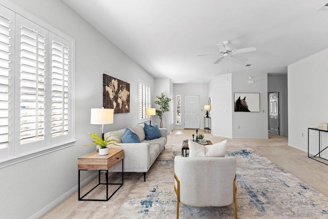 living area featuring baseboards, carpet floors, visible vents, and ceiling fan