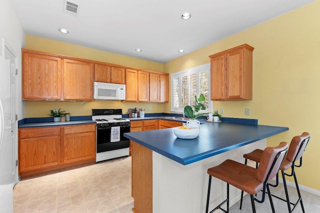 kitchen featuring white microwave, range with gas stovetop, dark countertops, and visible vents