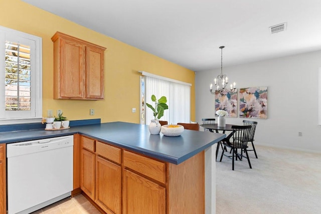 kitchen with dark countertops, light carpet, a peninsula, white dishwasher, and a notable chandelier