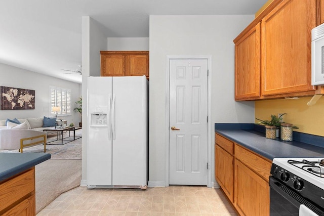 kitchen with dark countertops, brown cabinets, white appliances, and light carpet