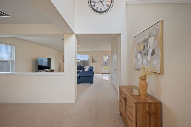 hallway featuring light carpet, visible vents, and a healthy amount of sunlight