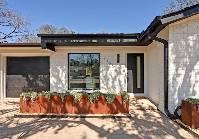 view of exterior entry featuring an attached garage and brick siding