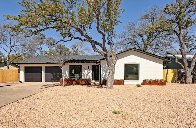 view of front of property featuring a garage, brick siding, driveway, and fence