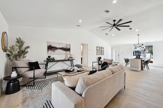 living room featuring ceiling fan with notable chandelier, vaulted ceiling, wood finished floors, and visible vents