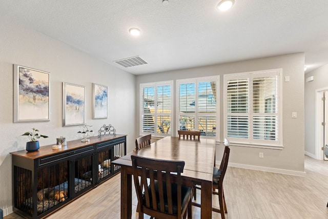 dining room featuring visible vents, baseboards, and light wood finished floors