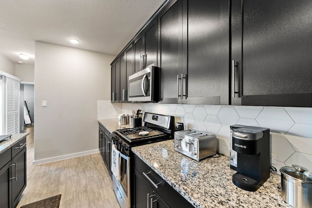 kitchen featuring dark cabinetry, tasteful backsplash, and stainless steel appliances