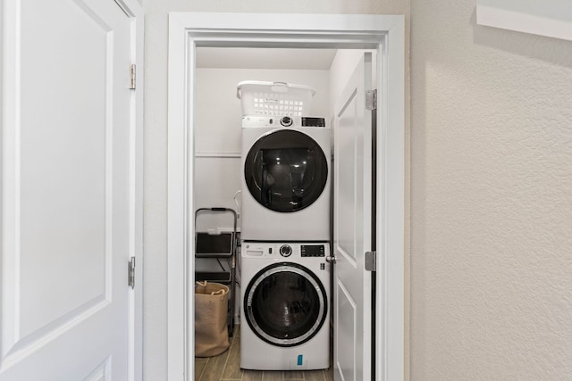 laundry area featuring laundry area, stacked washer and clothes dryer, and a textured wall