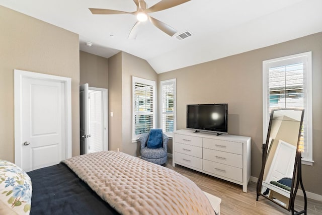 bedroom with visible vents, baseboards, vaulted ceiling, light wood-style flooring, and a ceiling fan