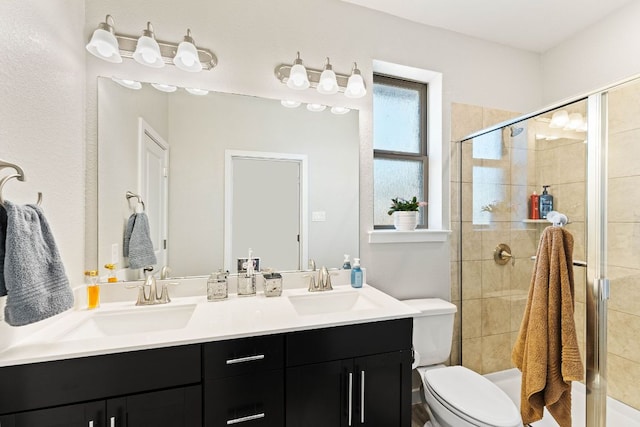 bathroom featuring a shower stall, toilet, double vanity, and a sink