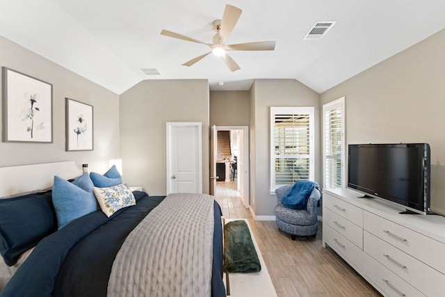 bedroom featuring light wood finished floors, visible vents, and vaulted ceiling