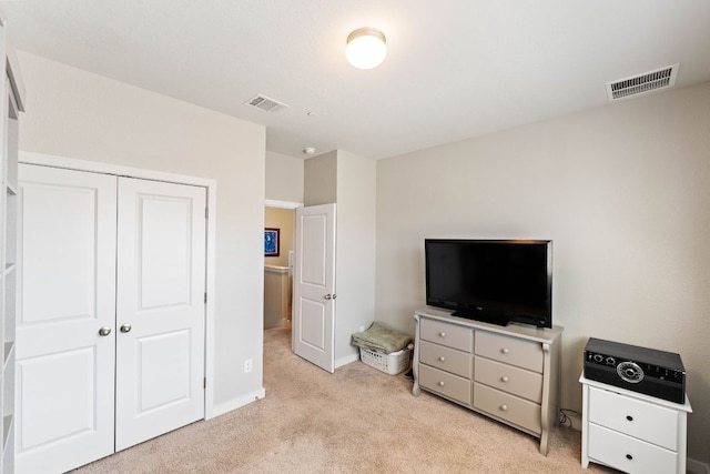 bedroom featuring light colored carpet, visible vents, and a closet