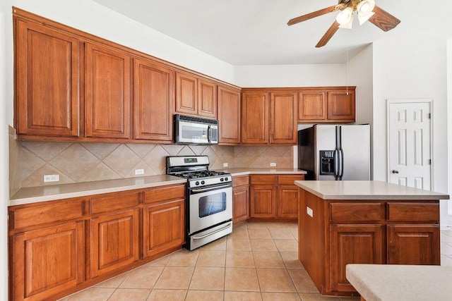 kitchen featuring tasteful backsplash, appliances with stainless steel finishes, brown cabinetry, light countertops, and light tile patterned floors