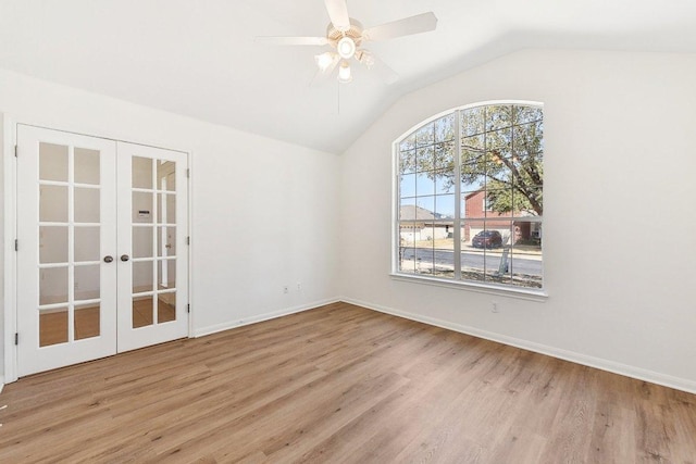 empty room with a ceiling fan, wood finished floors, french doors, baseboards, and lofted ceiling