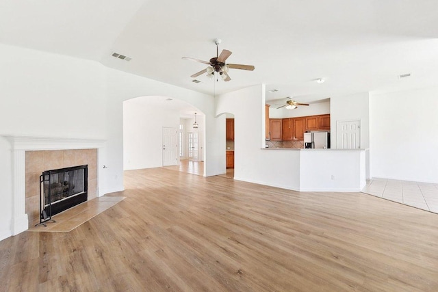 unfurnished living room featuring arched walkways, light wood-style floors, visible vents, and ceiling fan