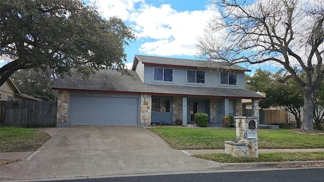 traditional-style house with driveway, stone siding, fence, a front yard, and an attached garage