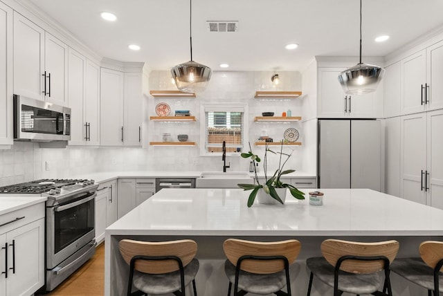 kitchen featuring a sink, open shelves, a breakfast bar, and stainless steel appliances