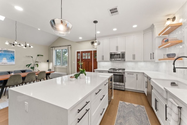 kitchen featuring visible vents, a sink, light countertops, stainless steel appliances, and open shelves