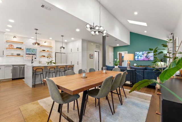 dining room with light wood-type flooring, visible vents, vaulted ceiling with skylight, and recessed lighting