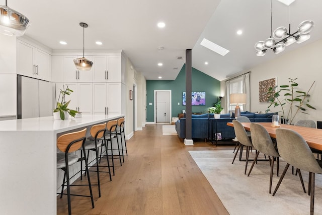 dining area featuring vaulted ceiling with skylight, recessed lighting, and light wood-style flooring