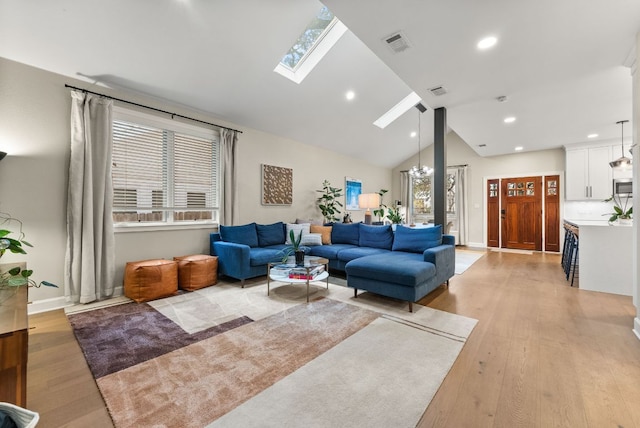 living room featuring light wood finished floors, visible vents, recessed lighting, and a skylight