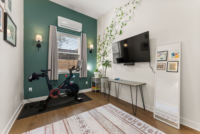 workout room featuring baseboards, wood finished floors, and a wall unit AC