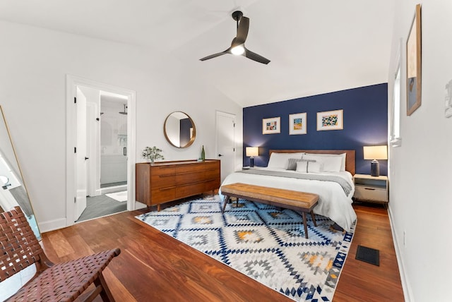 bedroom with visible vents, ensuite bathroom, wood finished floors, baseboards, and vaulted ceiling