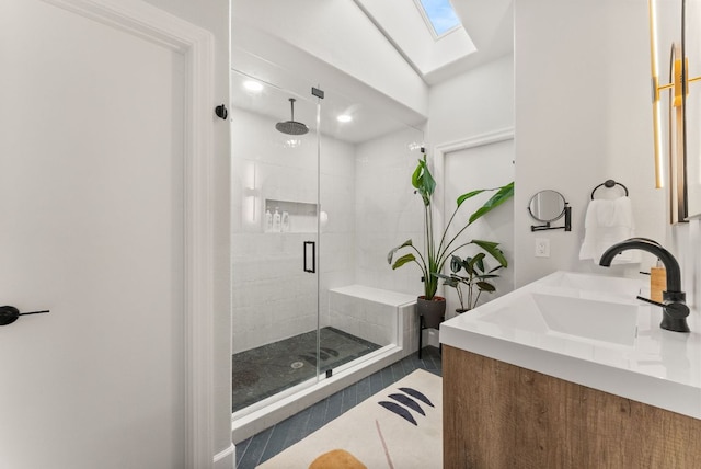 full bathroom featuring double vanity, a skylight, a sink, tile patterned flooring, and a shower stall