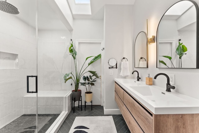 full bathroom with double vanity, a shower stall, a skylight, and a sink