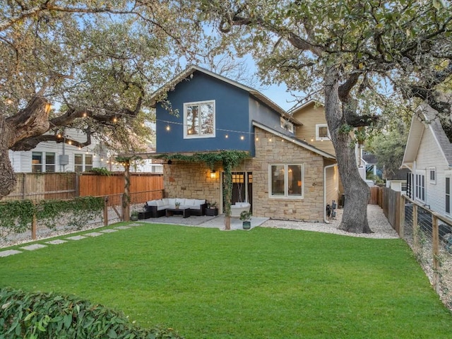 back of property with a yard, stone siding, an outdoor living space, and a fenced backyard