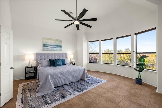 bedroom featuring a ceiling fan, baseboards, visible vents, a towering ceiling, and tile patterned floors