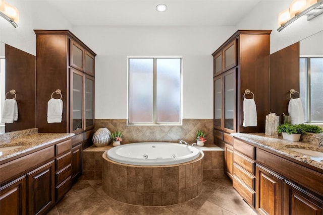 full bathroom featuring a wealth of natural light, two vanities, a whirlpool tub, and a sink