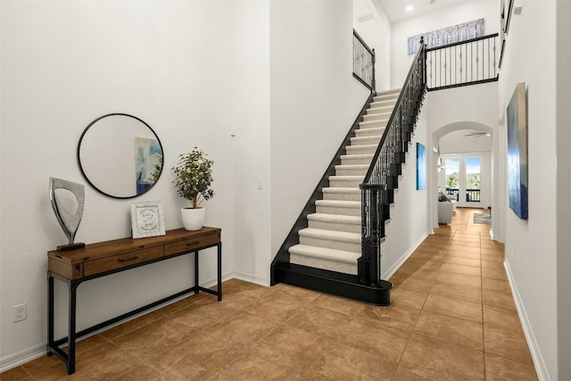 entryway with arched walkways, stairway, a high ceiling, and baseboards