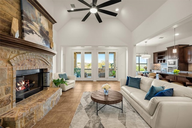 living room featuring visible vents, high vaulted ceiling, a ceiling fan, a stone fireplace, and tile patterned flooring