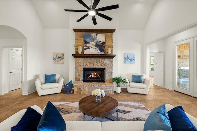 living area with high vaulted ceiling, a stone fireplace, ceiling fan, and tile patterned flooring