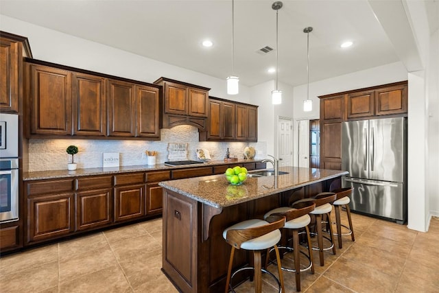 kitchen with visible vents, dark stone counters, a sink, appliances with stainless steel finishes, and tasteful backsplash