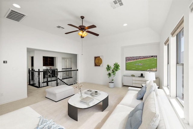 carpeted living area with lofted ceiling, a ceiling fan, and visible vents