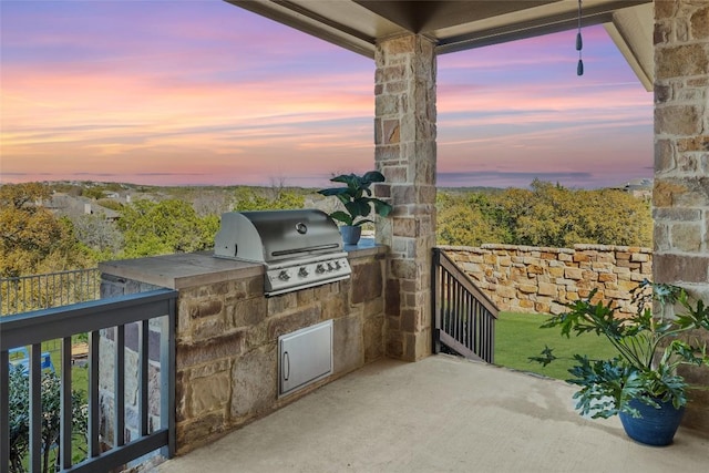 patio terrace at dusk with an outdoor kitchen and grilling area