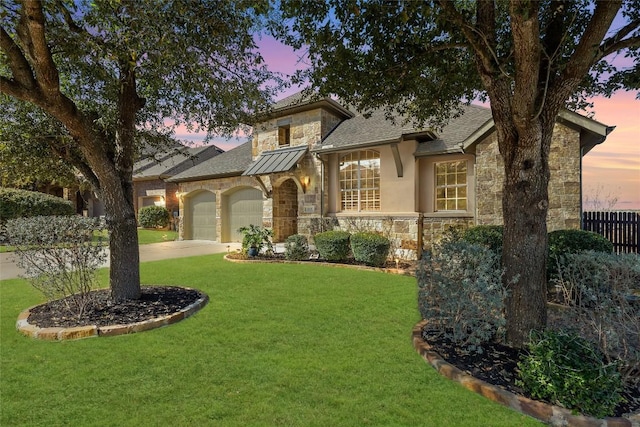 view of front of home with concrete driveway, a garage, stone siding, and a yard