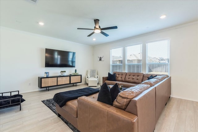 living room with light wood-style flooring, a ceiling fan, and ornamental molding