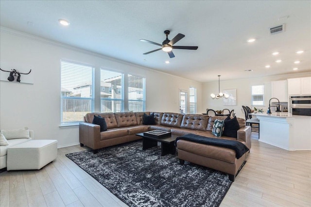 living room with visible vents, recessed lighting, ornamental molding, light wood-style floors, and ceiling fan with notable chandelier