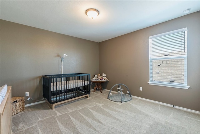 bedroom with a nursery area, baseboards, and carpet