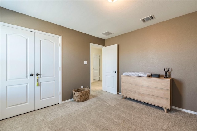 bedroom with baseboards, visible vents, a closet, and light carpet