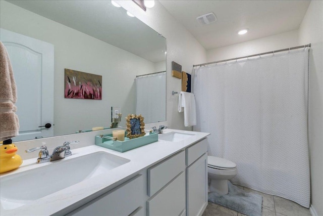 bathroom featuring double vanity, toilet, visible vents, and a sink