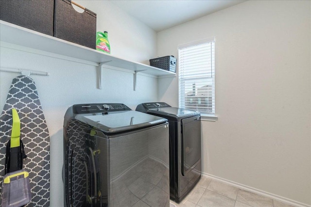 washroom featuring laundry area, light tile patterned floors, washing machine and dryer, and baseboards