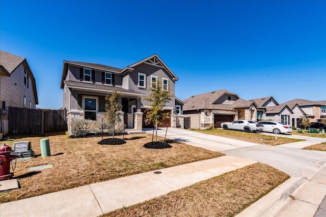 view of front of property with driveway, stone siding, fence, a residential view, and an attached garage