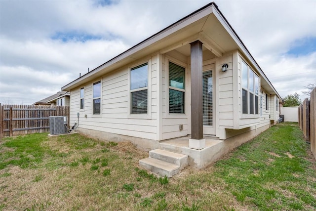 view of property exterior with a fenced backyard, cooling unit, and a yard