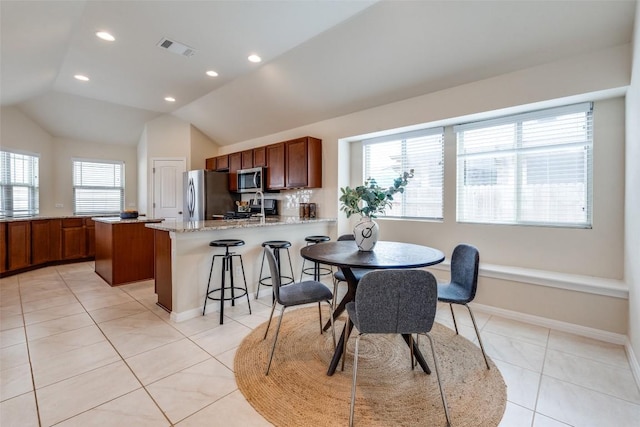 dining space with light tile patterned floors, visible vents, baseboards, and vaulted ceiling