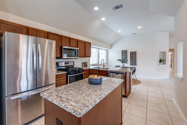 108 Trailstone Dr, Bastrop, TX 78602 - kitchen with appliances with stainless steel finishes, a sink, a peninsula, vaulted ceiling, and a center island