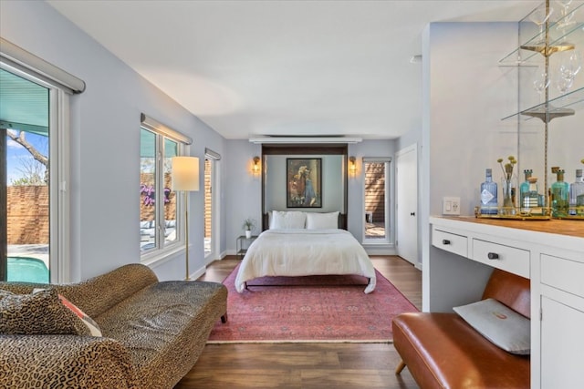 bedroom featuring dark wood finished floors, access to outside, and a bar