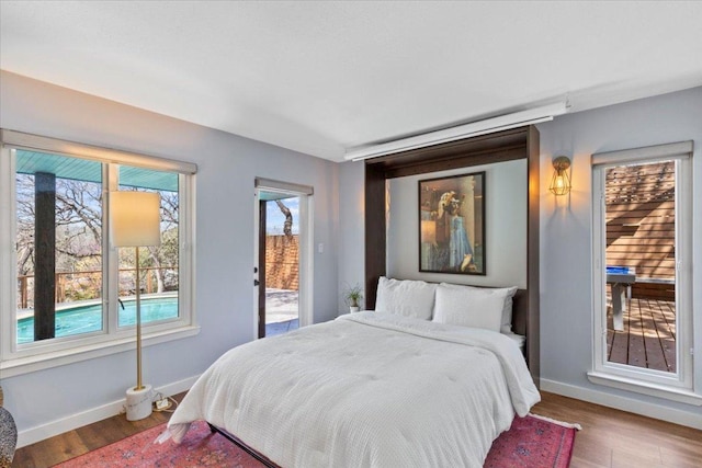 bedroom featuring access to exterior, wood finished floors, and baseboards